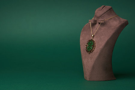 Gold necklace on green background. Jewelry chain with gold pendant. Luxury female jewelryの写真素材