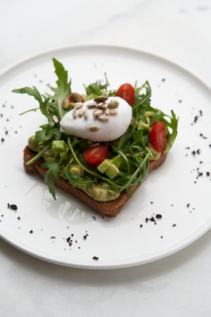 Poached egg toast with guacamole avocado sauce. Healthy breakfast with toasted bread and fresh...