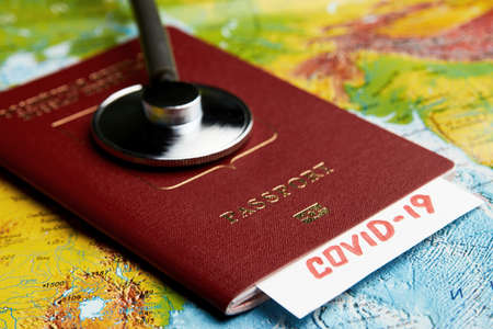 Coronavirus pandemic travel concept. COVID-19 medical test. COVID 19 traveling document on world map background with passport and medical stethoscopeの写真素材