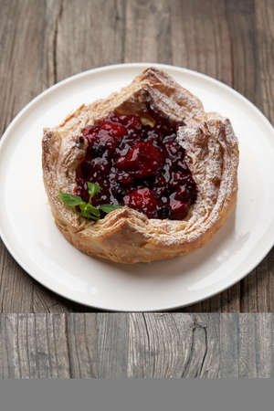 Puff pastry cake with berries on wooden background. Delicious pastries with cherry jam and...