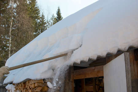 Wooden cottage covered with snow, close-up. Winter village house with snowy roof on sunny day over...