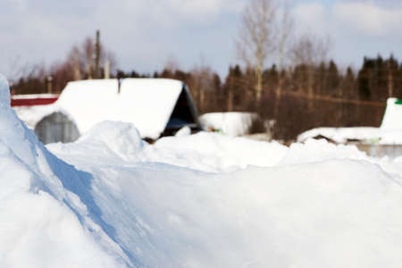 Wooden cottage covered with snow, close-up. Winter village house with snowy roof on sunny day over...