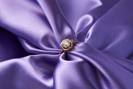 Engagement diamond ring on green satin background. Golden ring with a diamond, close-up. Luxury female jewellery, close-up. Selective focusの写真素材