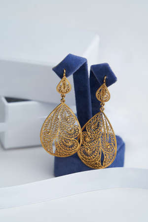 Vintage earrings on white background with copy space, close-up. Golden earrings on display standの写真素材