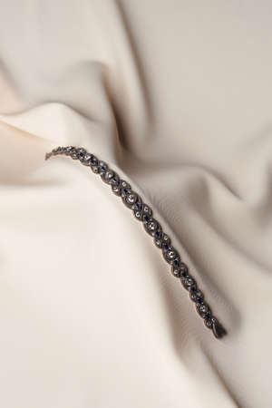 Platinum bracelet with diamonds and sapphire on pastel silk background. White gold bracelet with brilliant gemstones, close-up. Elegant woman jewelryの写真素材