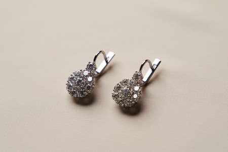 Platinum earrings with diamonds, close-up. White gold earrings with brilliant gem. Elegant female jewelry, selective focusの写真素材