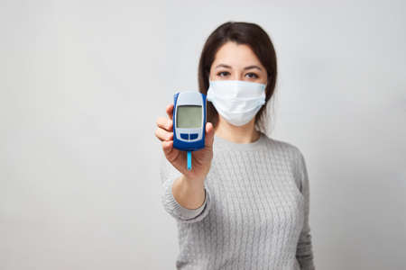 Woman with blood glucose meter. Young woman testing her blood sugar level.の写真素材
