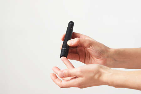 Woman using lancet pen. Young woman testing her blood sugar level.