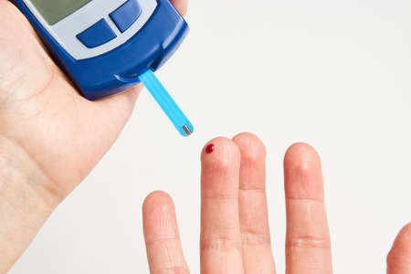 Woman with blood glucose meter. Young woman testing her blood sugar level.