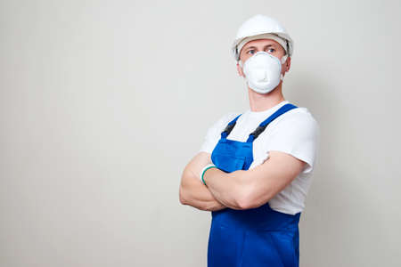 Worker man wearing face mask and protective hard hat. Young engineer worker wear a white helmet and...