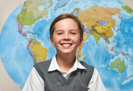 Portrait of smiling boy looking at camera. Happy smiling school boy on a blue map background,...