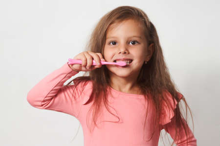 Little child girl brushing her teeth on white background. Beautiful girl with toothbrush, healthy dental conceptの写真素材