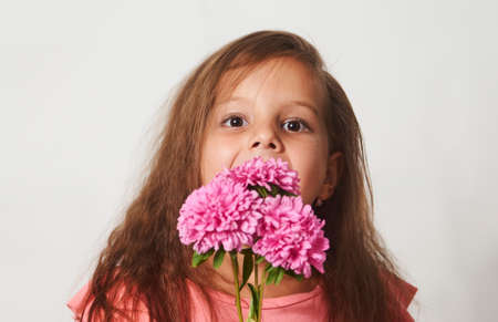 Portrait of a little girl with a flowers bouquet on a white background with copy space, close-upの写真素材