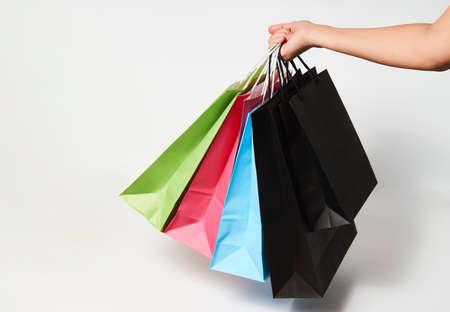 Woman hand with shopping bags on white background with copy space. Woman holding colorful paper...