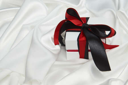 Christmas gift box with ribbon on white silk background with copy space, close-upの写真素材