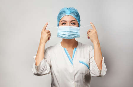 Doctor wearing medical mask, close-up portrait. Young woman doctor with face mask on white background. Covid 19, coronavirus concept.の写真素材