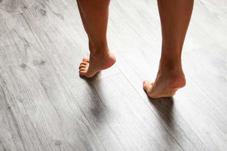 Female leg stepping on floor scales, close-up. Woman and weighing scales at home. Diet, healthy lifestyle, loss weight, slim concept.の写真素材