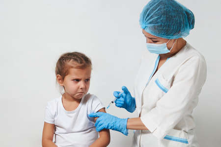 The concept of vaccination. Female doctor injecting vaccine to girl. Young nurse doctor and child girl on white background with copy space, close-upの写真素材