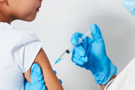 Female doctor injecting vaccine to girl. Young nurse doctor and child girl on white background with copy space, close-up. The concept of vaccinationの写真素材