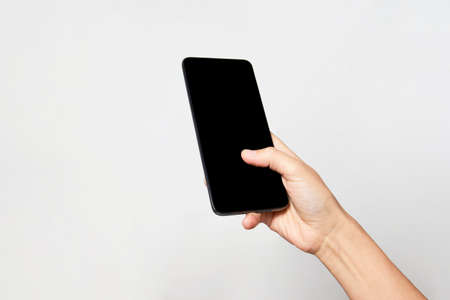 Woman holding smartphone with black screen. Woman hand holding phone on white background with copy...