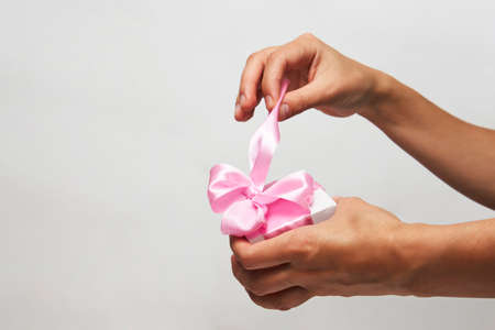 Female hands holding small gift box with ribbon on white background. Christmas, New Year, Valentine's day and birthday conceptの写真素材