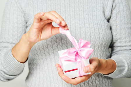Female hands holding small gift box with ribbon on white background. Christmas, New Year, Valentine's day and birthday conceptの写真素材