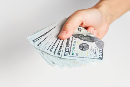 Hand with money isolated on white background with copy space. Woman hand giving dollar money,...