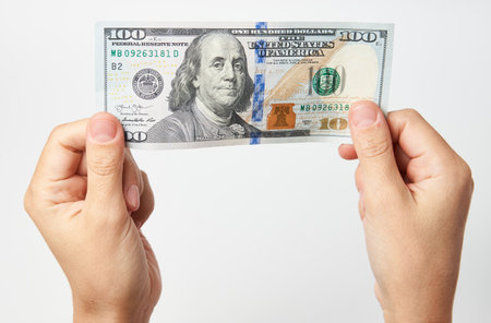 Hand with money isolated on white background with copy space. Woman hand giving dollar money,...