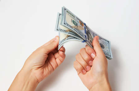 Woman counting dollars money, top view. Hands holding a dollar bills on white background, close-up. Salary, earning and savings conceptの写真素材
