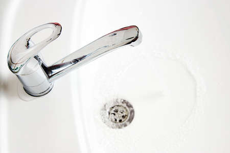 Water tap with flowing water into white sink. Running water faucetの写真素材