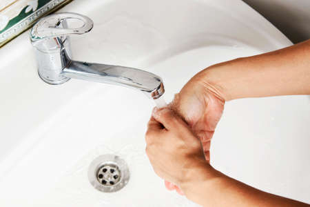 Woman washing hands with the water tap. Washing hands with soap, close-up.irus prevention, hygiene conceptの写真素材