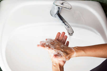 Woman washing hands with the water tap. Washing hands with soap, close-up. virus prevention, hygiene conceptの写真素材