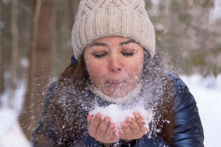Beautiful woman in a winter forest enjoying first snow, outdoor