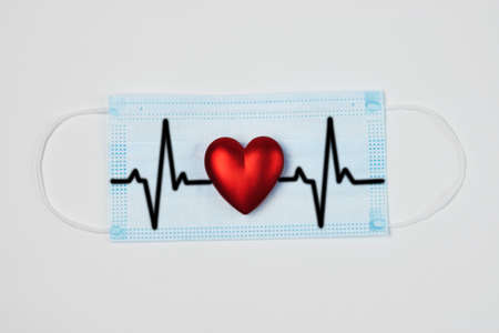 Medical face mask and red heart on white background. Healthcare and medical concept. Coronavirus disease covid-2019 heart attackの写真素材