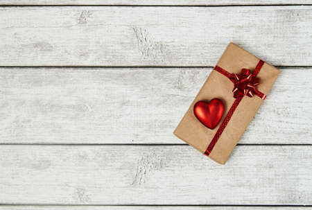 Valentine's Day background February 14th. Gift box with bow ribbon and red heart on wooden...