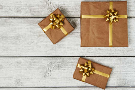 Gift boxes wrapped in craft paper with bow tie on wooden background with copy space