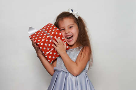 Child girl with christmas gift box on a white background with copy space. Portrait of a 5 years old...
