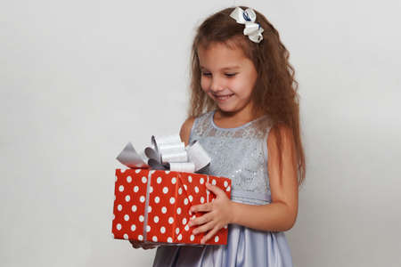 Child girl with christmas gift box on a white background with copy space. Portrait of a 5 years old...