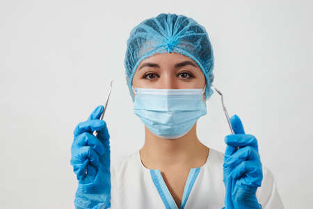 Portrait of dentist woman with dental tools on white background with copy space. Young dentist doctor with stomatology equipment. Healthy teeth concept.の写真素材