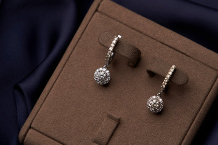 Platinum earrings and ring with a diamond gemstone on a blue silk background, close-up. Selective focus. Luxury female jewelryの写真素材