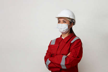 Portrait of a woman worker wearing medical mask and protective hard hat. Young engineer worker wear a white helmet and face mask. virus Hygiene, safety conceptの写真素材