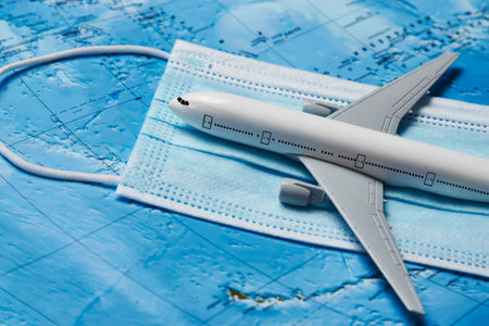 Traveling during COVID-19 pandemic. Travel and coronavirus concept with medical face mask and plane...