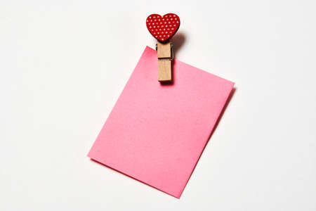Clothespin with red heart and note paper on a white background with copy space for text. Love and Valentines day backgroundの写真素材