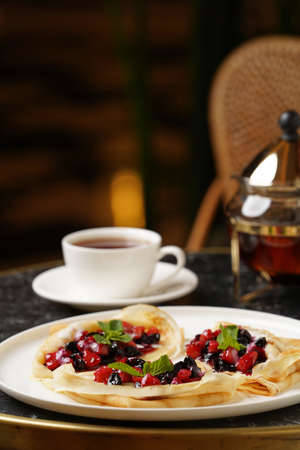 Crepes served with fresh berries and apples. Breakfast menu, traditional pancakes on a white plateの写真素材