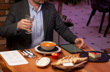 Man with menu in a restaurant taking order at table, close-up. Waiter taking the order from a...