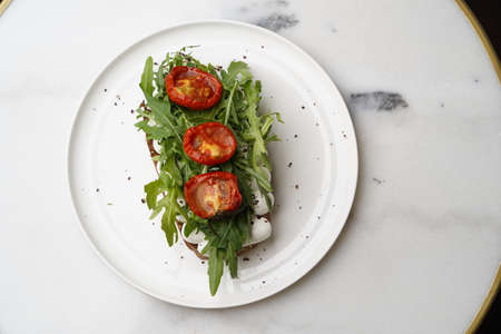 Traditional italian bruschetta with roasted tomatoes mozzarella cheese and herbs on a white plate