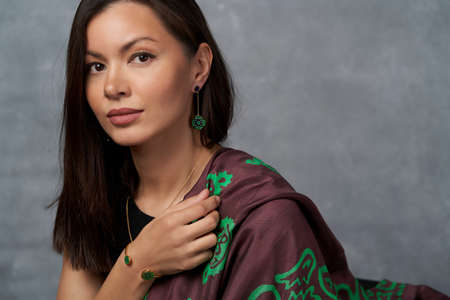 Portrait of pretty woman with dark hair and brown eyes. Beautiful young woman with silk scarf on...