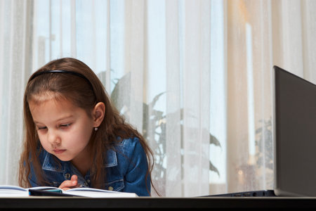 Preschool education. Child girl enjoy e-learning on computer notebook. Online learning and distance study concept.の写真素材