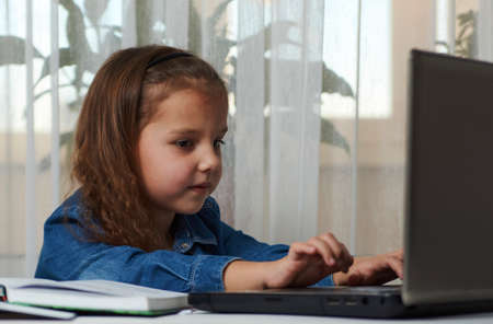 Preschool education. Child girl enjoy e-learning on computer notebook. Online learning and distance study concept.の写真素材