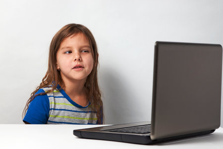 Online learning and distance study concept. Preschool education. Child girl enjoy e-learning on computer notebook at homeの写真素材